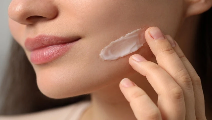 Woman applying facial moisturizer during a winter skincare routine to help keep her skin hydrated, soft, and healthy.